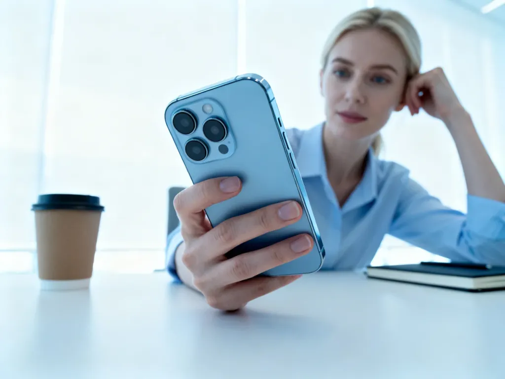 Smartfon Huawei P40 lite trzymany w dłoni, prezentujący elegancki design obiektywów aparatu na tle jasnego biura.